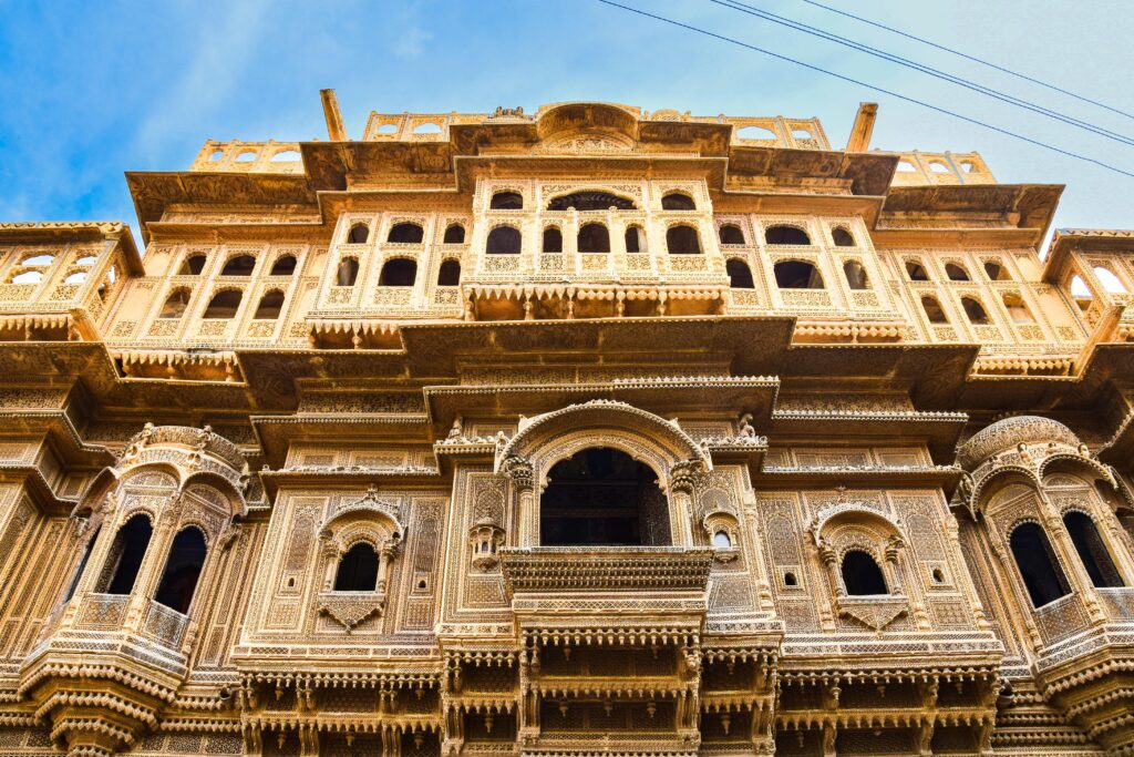 A detailed view of traditional Indian architecture with intricate carvings under a clear blue sky.